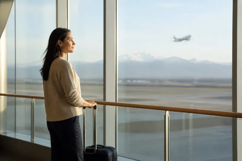 Mujer adulta observa un avión desde una terminal antes de decidir si se aproxima a la situación temida